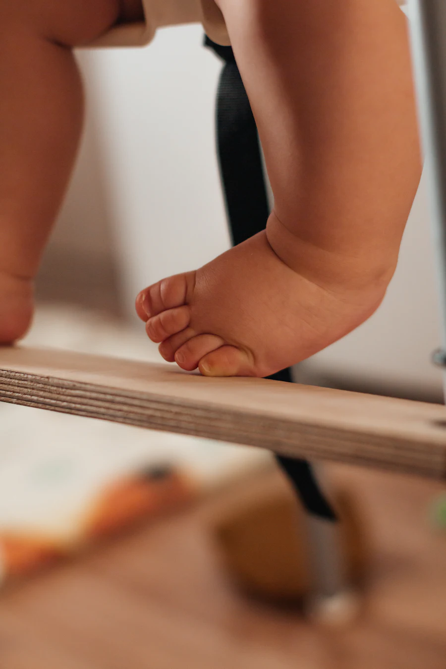 El pie de un bebé apoyado sobre una tabla de equilibrio de madera